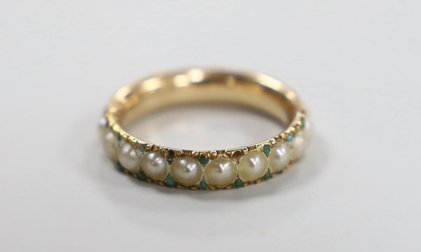 An antique yellow metal and split pearl set full eternity ring with green cabochon spacers, size K/L, gross weight 3 grams.